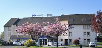 Un hotel con un cartel que dice "ibis budget hotel" y un estacionamiento con coches.