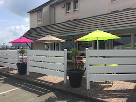 Un patio con vallas blancas, plantas en macetas y sombrillas coloridas.