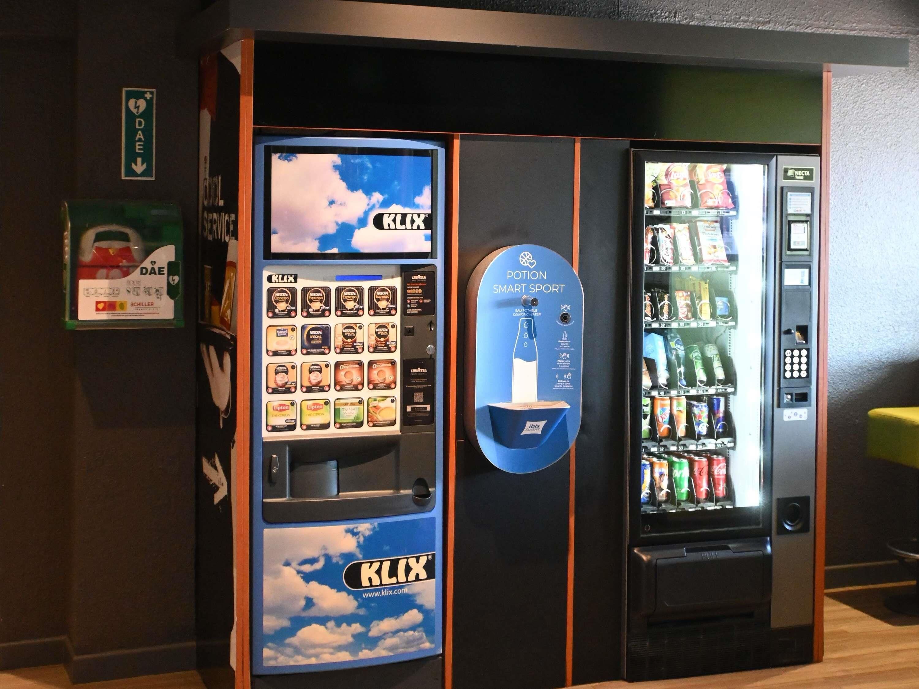 A vending machine with a blue sky and clouds design, a digital screen, and a selection of snacks and drinks.