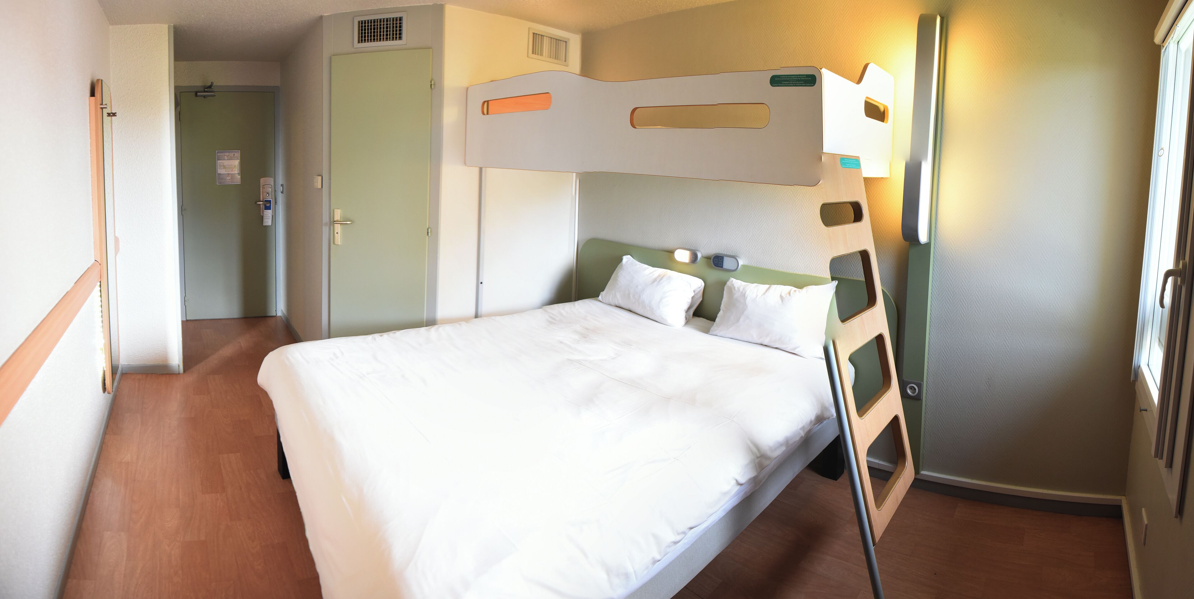 A hotel room with a large bed, a wooden headboard, a bedside table, and a nightstand.