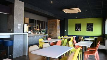 Interior modern d'un restaurant amb caires i taules de colors, i una barra amb un quadre de menú.