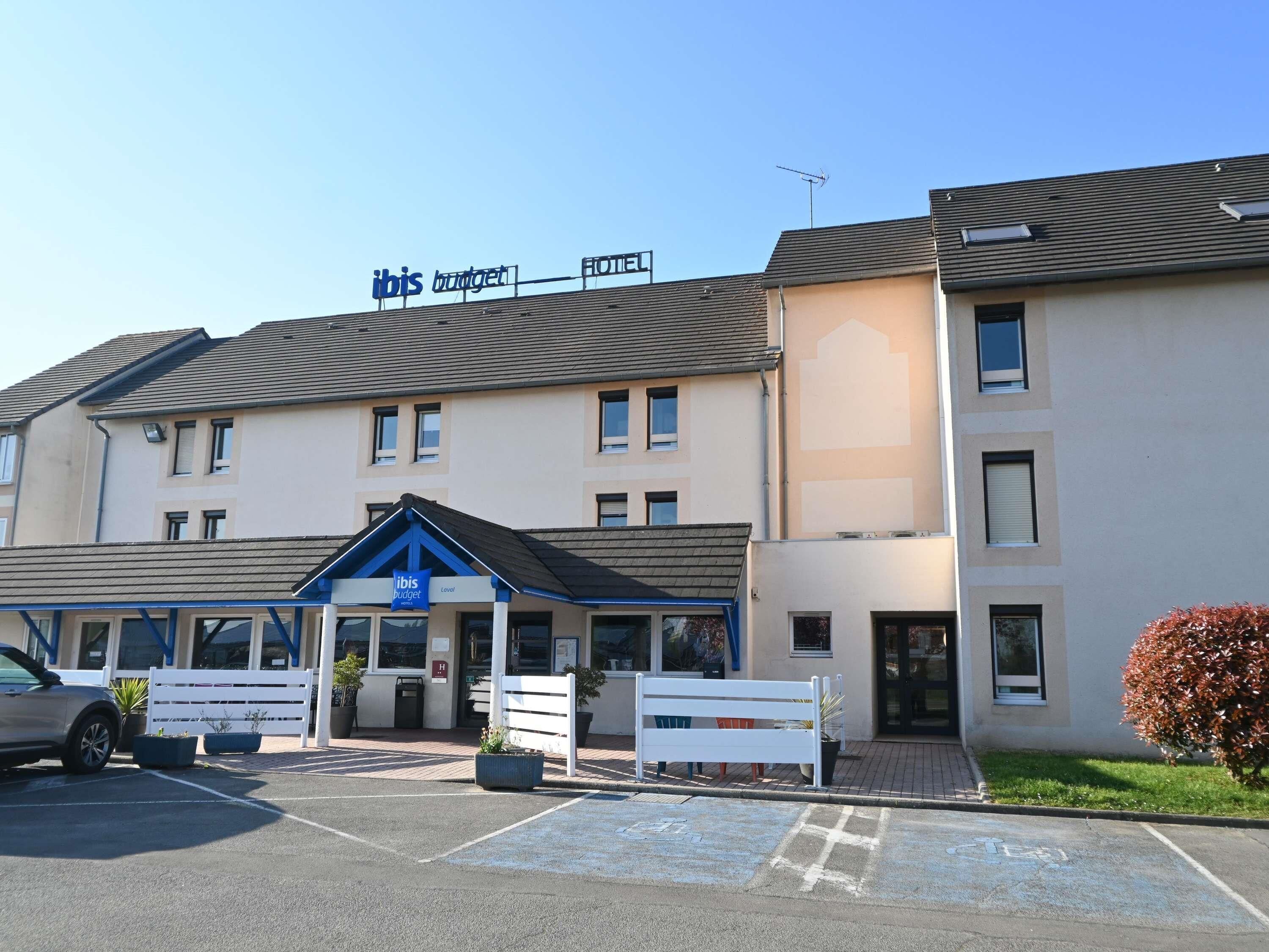 Un hotel llamado 'ibis budget' con aparcamiento, una entrada cubierta y un pequeño jardín.