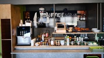 Un bancone di un bar con una macchina per il caffè, diversi cibi e una lavagna con il menu.