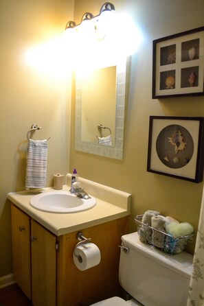 Un baño con lavabo, espejo, inodoro y un cuadro en la pared.