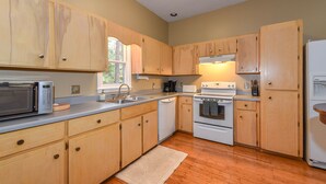 Una cocina con armarios de madera, microondas, lavavajillas, estufa y refrigerador.
