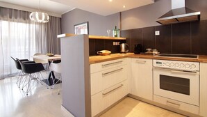 Une cuisine moderne dotée d’un four encastré, d’un plan de travail en bois et d’un coin repas avec une table et des chaises.