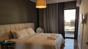 Une chambre d’hôtel avec un grand lit, une table de chevet, une lampe et une vue sur l’extérieur.