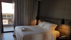 Une chambre d’hôtel avec un grand lit, une table de chevet, une lampe et une vue sur l’extérieur.