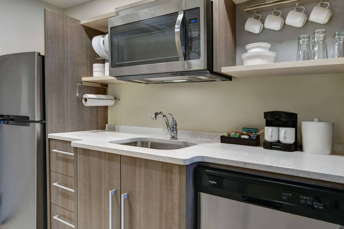 Eine moderne Küche mit einem Edelstahl-Kühlschrank, einer Mikrowelle, einem Geschirrspüler und einer Kaffeemaschine.