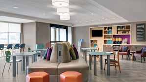 A modern hotel lobby with seating areas, tables, and a reception desk.