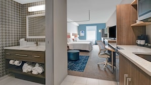 A modern hotel room with a bathroom, a bedroom, and a kitchenette.