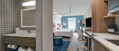 A modern hotel room with a bathroom, a bedroom, and a kitchenette.