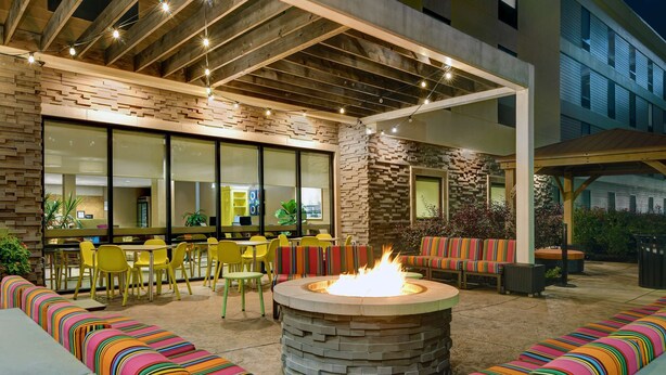 An outdoor seating area with a fire pit, yellow chairs, and colorful striped cushions.