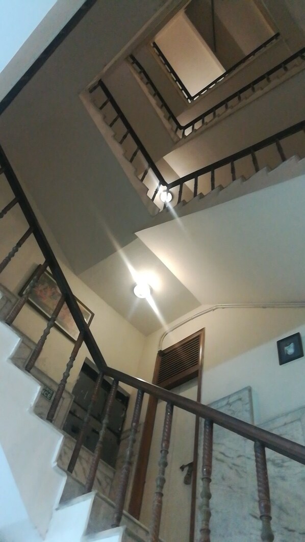Una escalera de varios niveles con barandillas de madera y una lámpara en la parte superior.