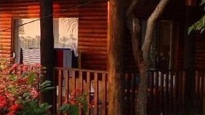 A wooden cabin with a porch, surrounded by greenery. - Viewpoint Lodge (Mbombela)