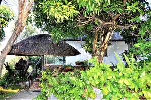 A house with a thatched roof, surrounded by lush greenery and a staircase leading to the entrance. - Viewpoint Lodge (Mbombela)