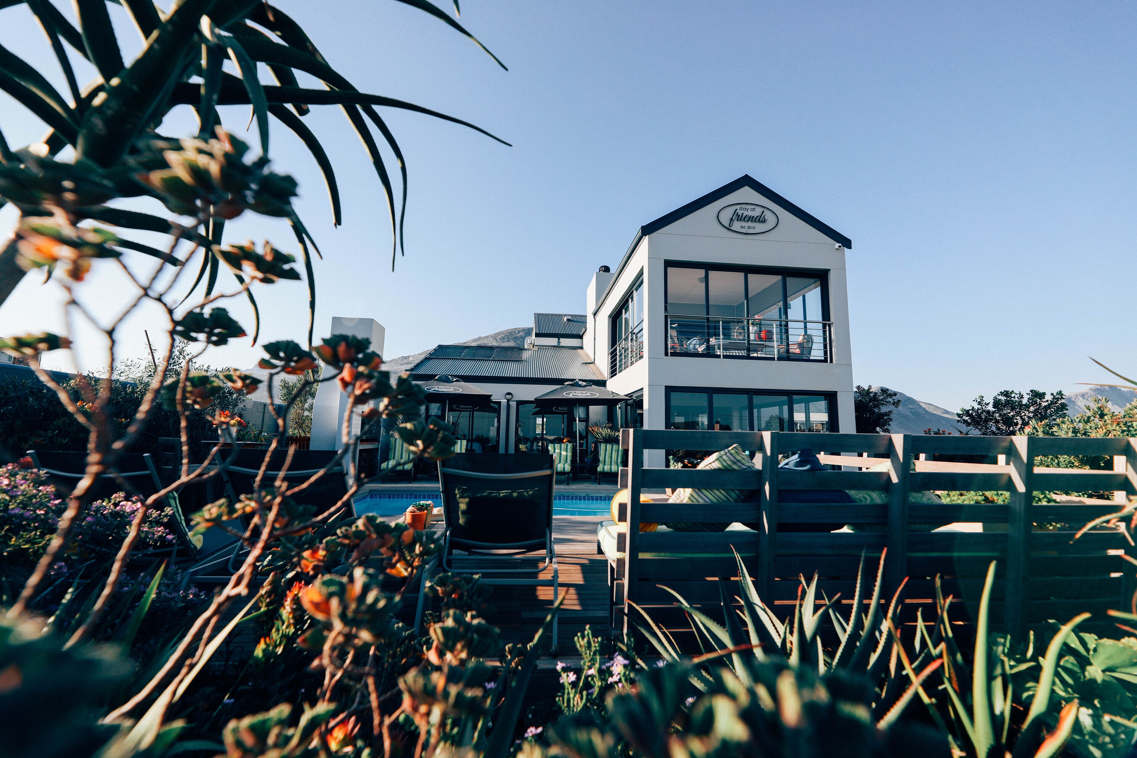 A modern two-story building with large windows, a balcony, and a pool area.
