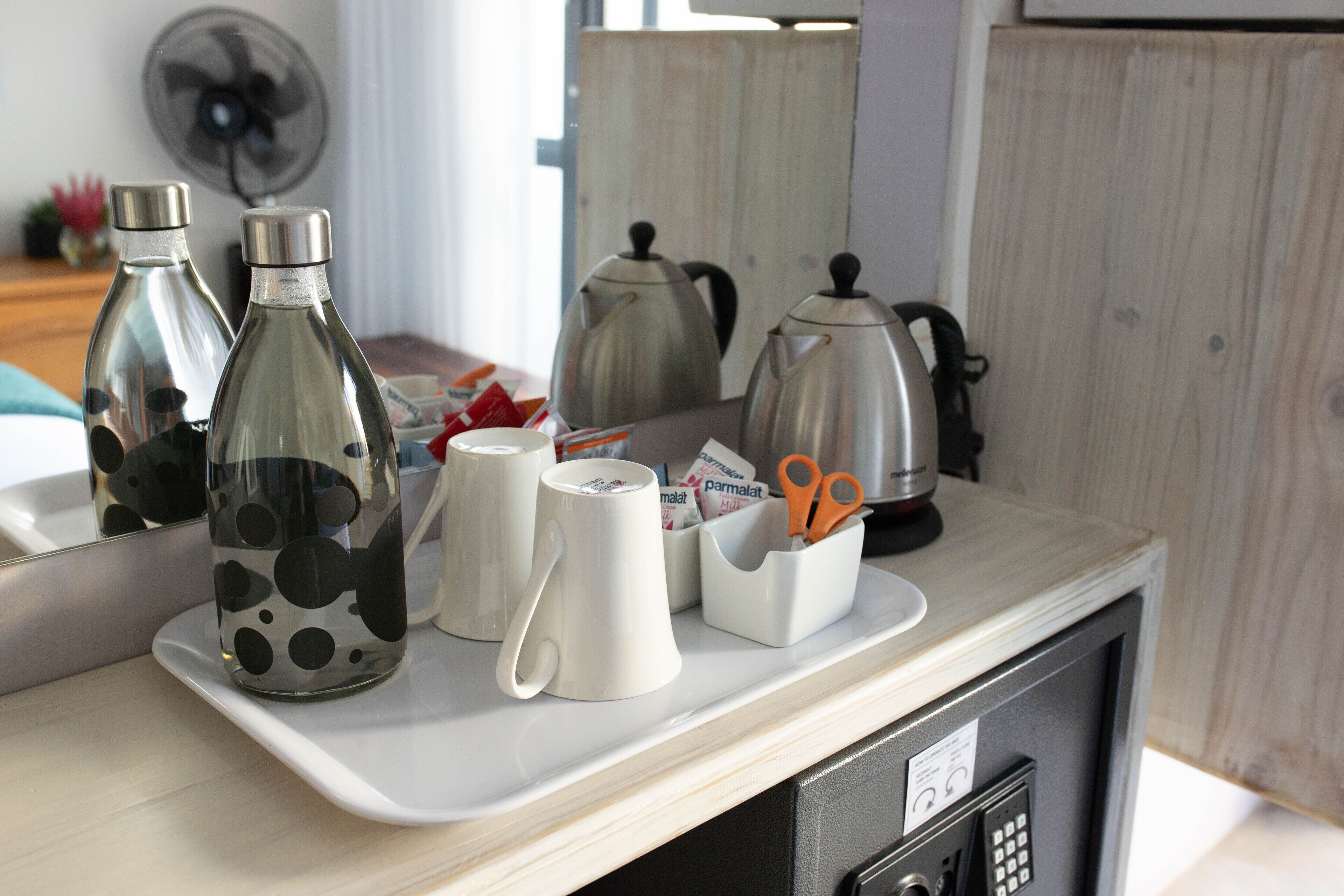 A kitchen counter with a coffee maker, a kettle, a mug, and a container holding scissors.