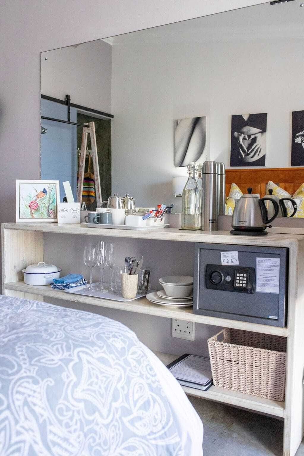 A hotel room with a bed, a bedside table with a radio, a microwave, a kettle, and a framed picture on the wall.