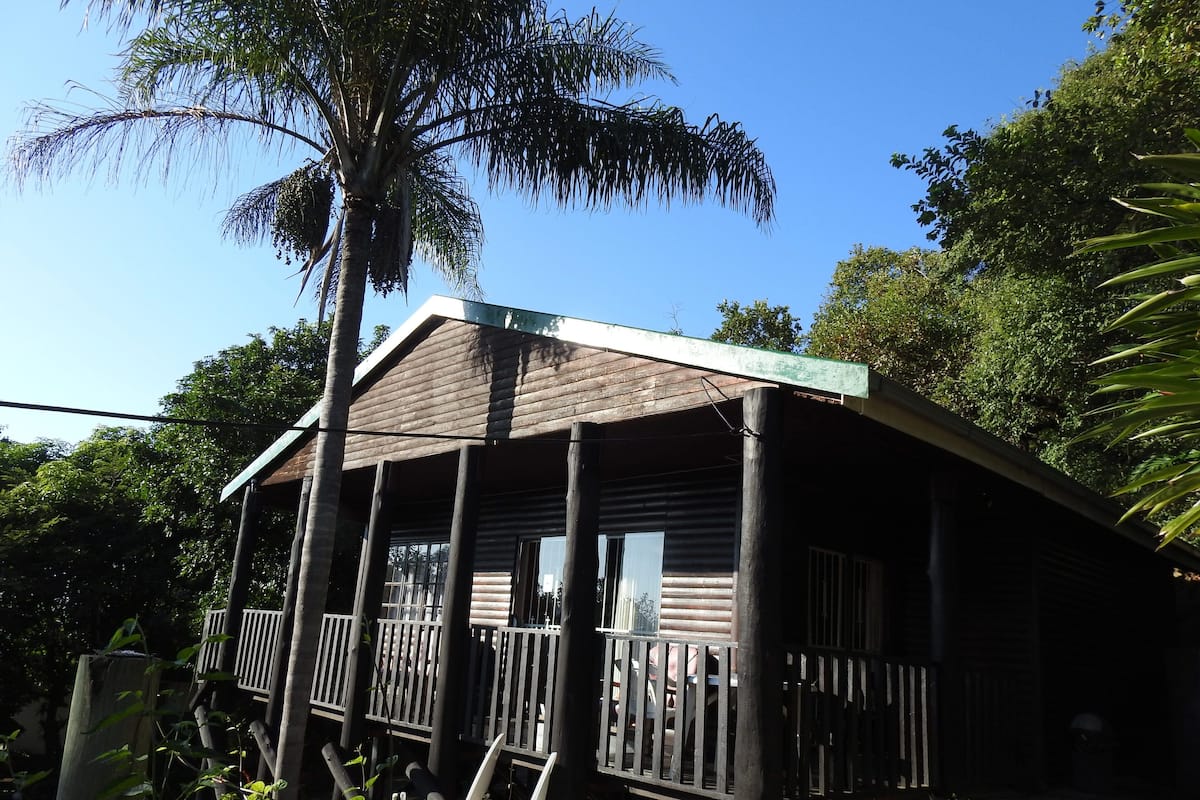 Ein Holzhaus mit Veranda, umgeben von üppigem Grün.