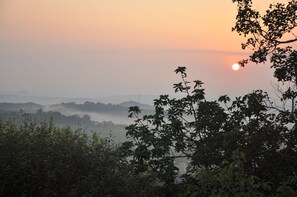 A sunrise over a misty landscape with dense foliage in the foreground. - Impala Niezel Lodge (Mbombela)