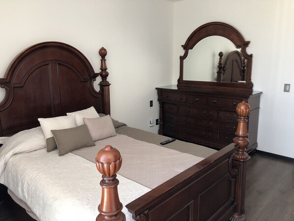 A bedroom with a wooden bed, a dresser, and a mirror.