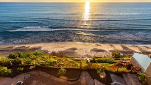 Une plage avec des vagues, un coucher de soleil et une vue sur l’océan.