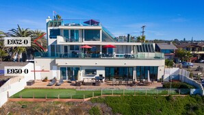 A modern two-story house with a balcony, outdoor seating, and a view of the ocean. - Seaside Luxury Duplex with Putting Green E950-0 (Encinitas)