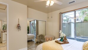 A bedroom with a large bed, a chair, a mirror, and a window with a view of the outside. - Seaside Luxury Duplex with Putting Green E950-0 (Encinitas)