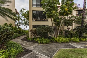 A modern building with a two-story structure, surrounded by lush greenery and palm trees.