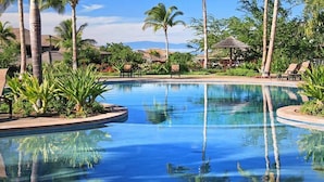 Ein Pool mit Liegestühlen und Palmen.