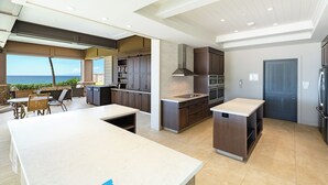 A modern kitchen with a large island, built-in cabinets, and a view of the ocean.