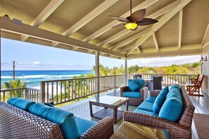 Relax in this ocean-view seating area with wicker sofas and chairs, surrounded by a white railing.