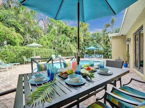 An outdoor dining area with a pool, surrounded by lush greenery. - Vidal Manor | Walk to Wilton Drive + Heated Pool (Wilton Manors)