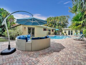A poolside area with a circular seating arrangement, a pool, and a covered patio. - Vidal Manor | Walk to Wilton Drive + Heated Pool (Wilton Manors)