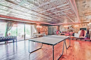 Een kamer met een tafeltennistafel, houten wanden en een groot raam.