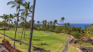 Ein Golfplatz mit Palmen und Blick auf den Ozean.
