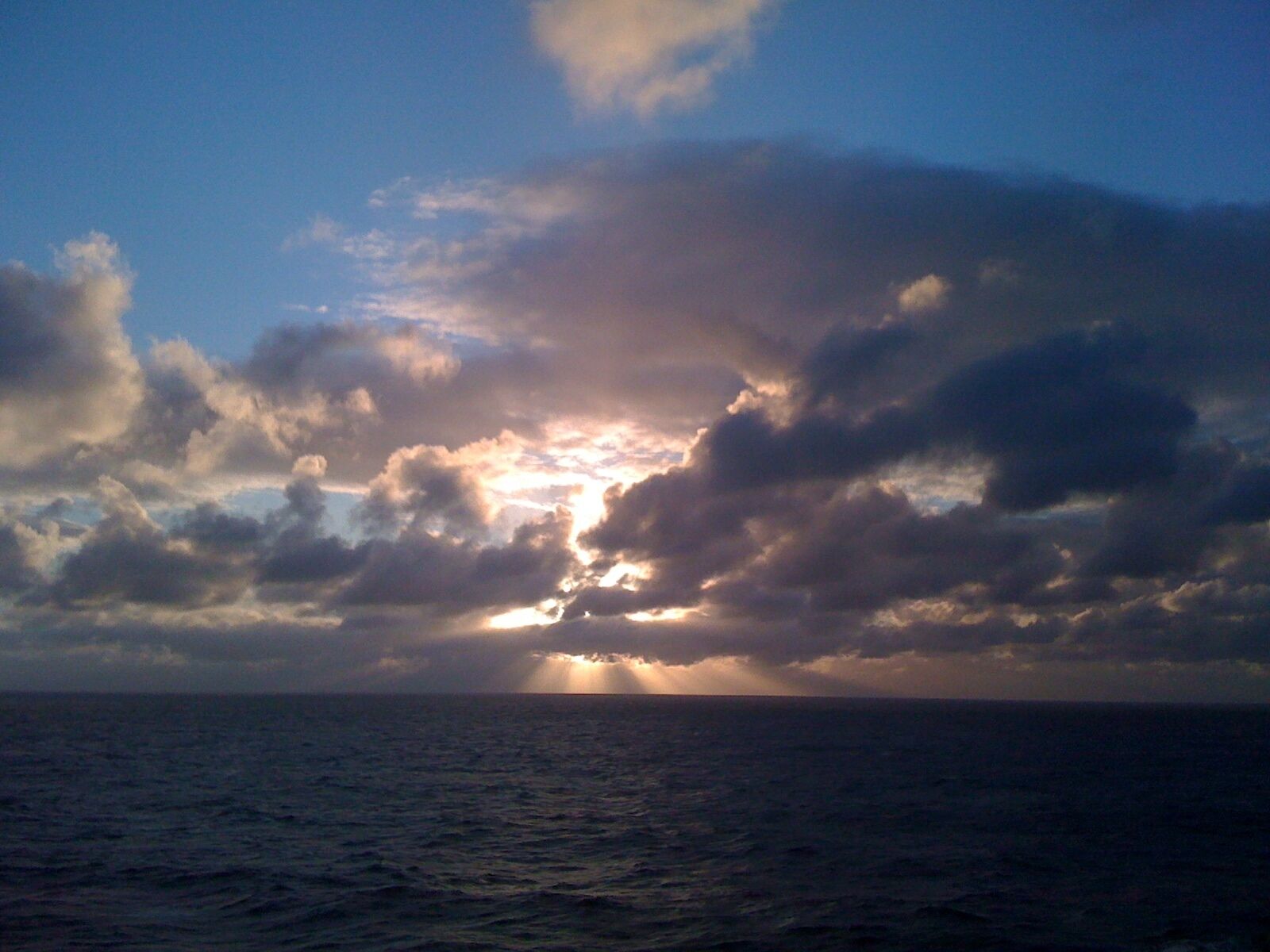 Een zonsondergang boven de oceaan met wolken.