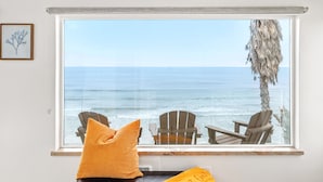 A room with a large window overlooking the ocean, featuring two wooden chairs and a cushion. - Bluff-Top Beauty With Ocean Views - 1086 (Encinitas)