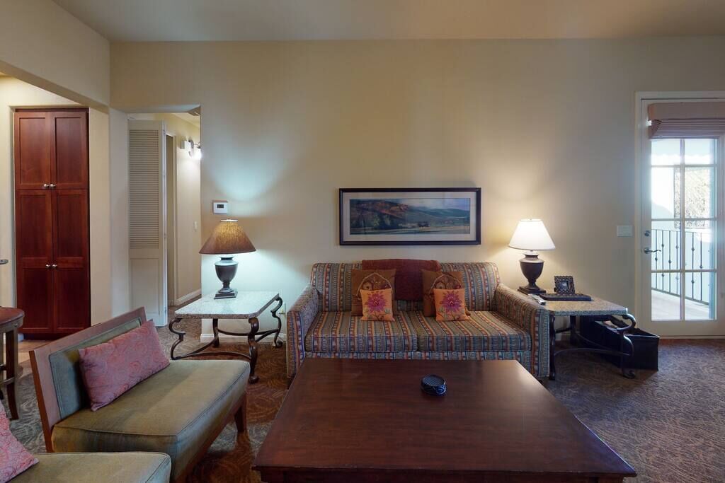 A living room with a sofa, a coffee table, a lamp, and a painting on the wall.