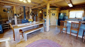 A rustic cabin interior with a wooden dining table, benches, a kitchen area, and a staircase. - W-W: Canyon View Cabin, An Epic Family Retreat (Monticello)