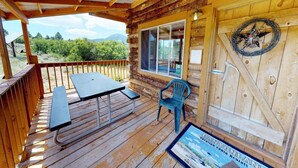 A wooden cabin with a covered porch, a picnic table, a chair, and a sign for vacation rentals. - W-W: Canyon View Cabin, An Epic Family Retreat (Monticello)
