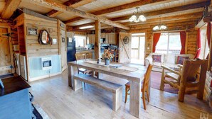 A rustic cabin interior with a wooden dining table, benches, a kitchen area, and a living space with a sofa and chairs. - W-W: Canyon View Cabin, An Epic Family Retreat (Monticello)