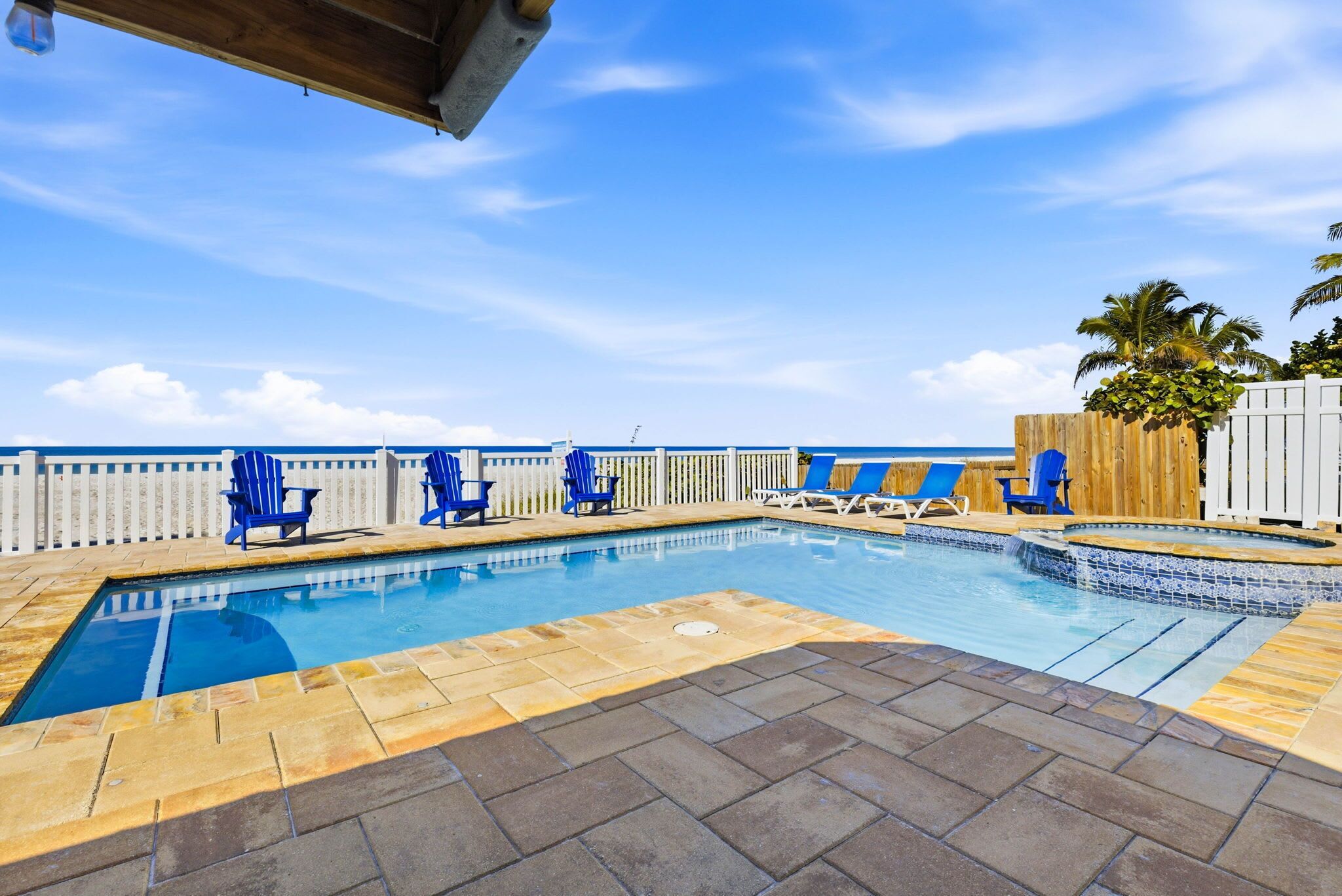 A swimming pool with blue chairs and a wooden deck.