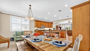 A spacious kitchen with wooden cabinets, a dining table set for four, and a large window providing natural light. - Isla Bonita 4BR Villa in Indian Rocks Beach (Indian Rocks Beach)