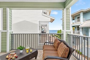 A balcony with a wicker sofa, a table with snacks and drinks, and a view of a building with balconies.