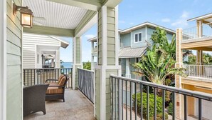 A covered balcony with outdoor furniture, a view of the ocean, and a house with a balcony. - Isla Bonita 4BR Villa in Indian Rocks Beach (Indian Rocks Beach)