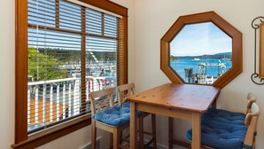 A corner room with a wooden table and chairs, a large window with blinds, and a view of a marina and water. - San Juan Island, Yakima Suite #1901 (Friday Harbor)