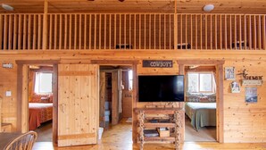 Een cabin interieur met een vide, een televisie en een bed met een bord waarop 'Cowboy's' staat.