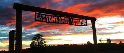 A sign reading "CANYONLANDS LODGING" against a sunset sky.